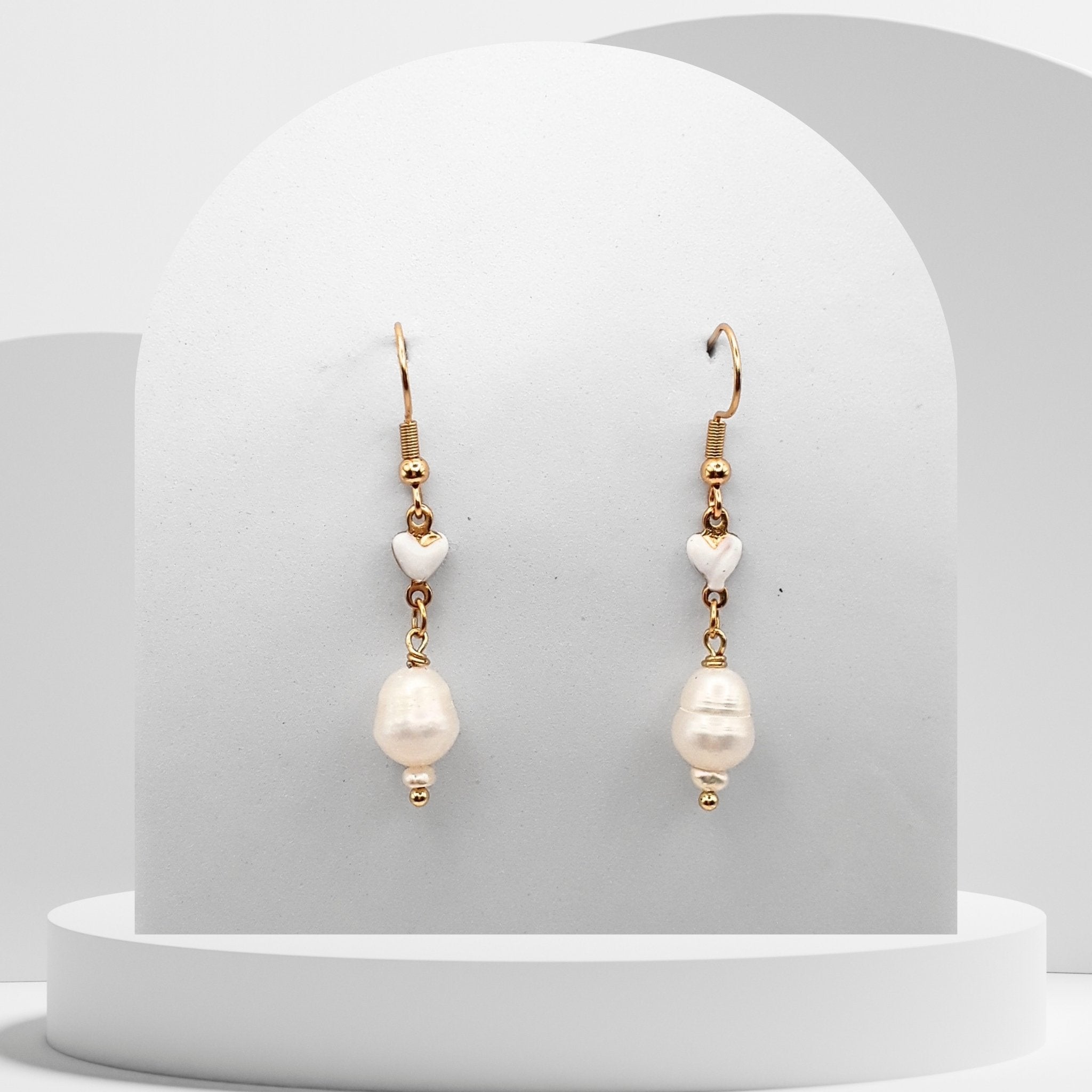 Freshwater Pearl gold‑plated stainless steel earrings feature a natural white 7 mm pear‑shaped pearl suspended from a small ceramic heart.