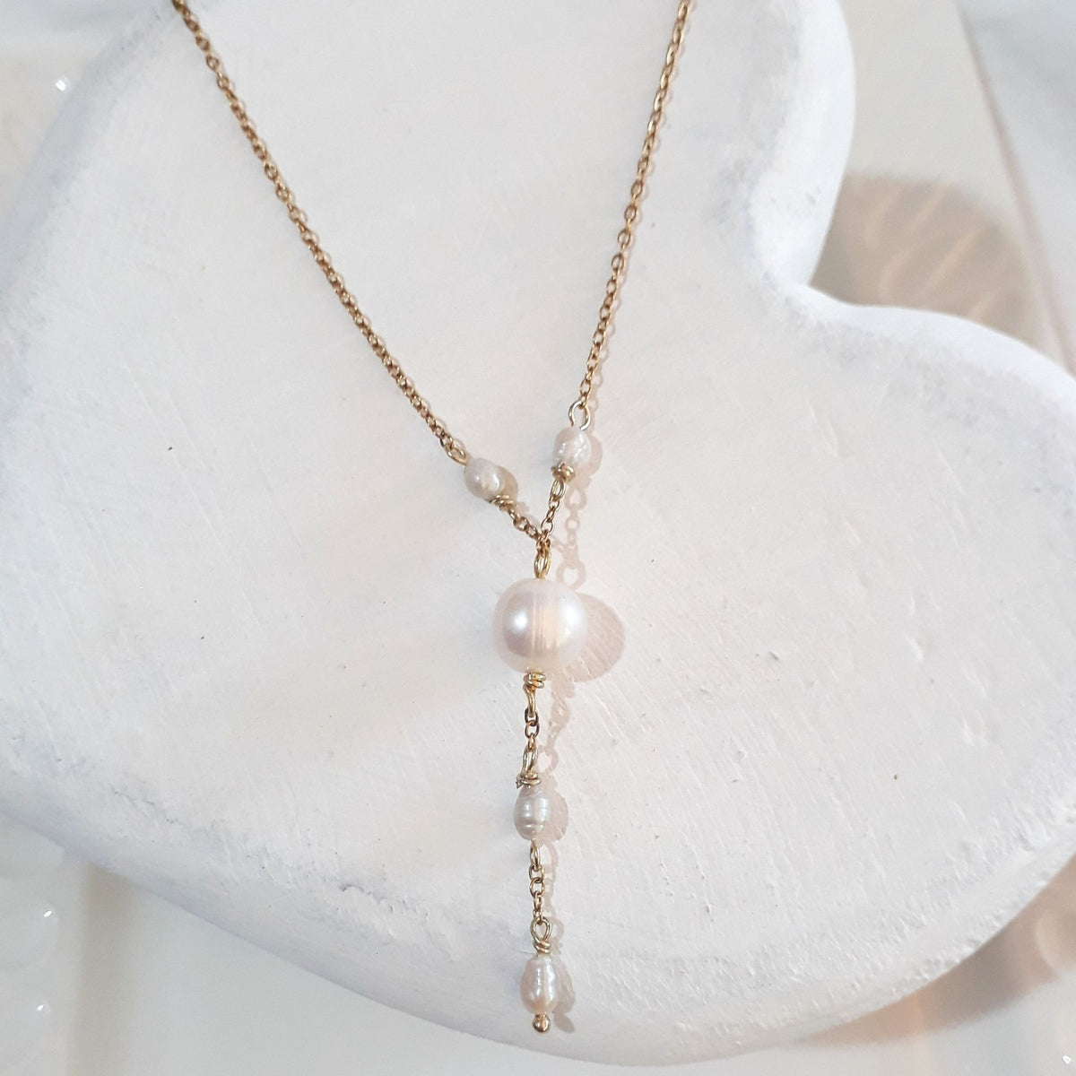 This handmade Y necklace brings together the soft lustre of a white freshwater pearl and four smaller pearl accents along a warm gold-plated Stainless Steel chain.
