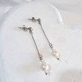 White pear-shaped freshwater pearls between small rice pearls, suspended from fine silver-tone cable chains and ball studs.