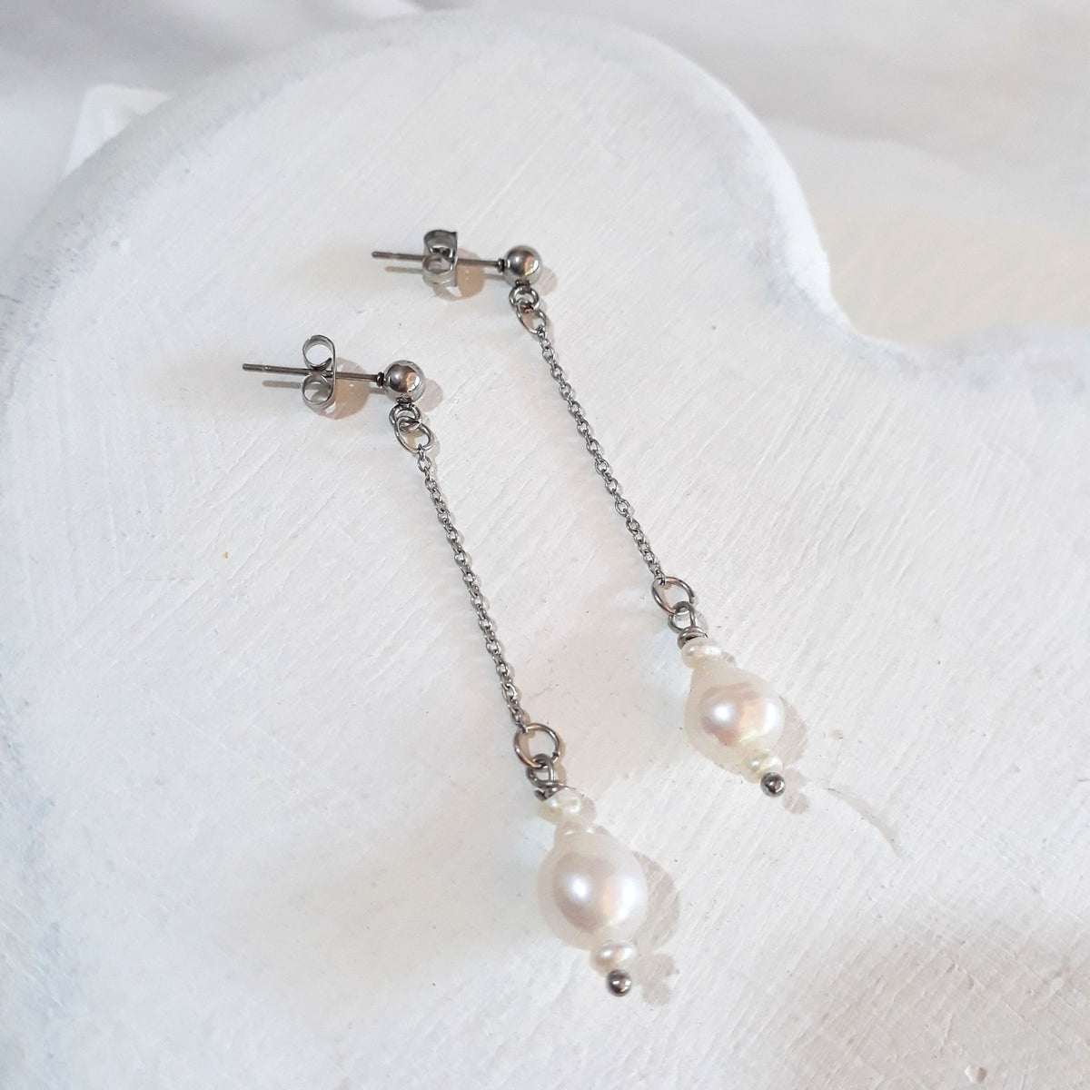 White pear-shaped freshwater pearls between small rice pearls, suspended from fine silver-tone cable chains and ball studs.
