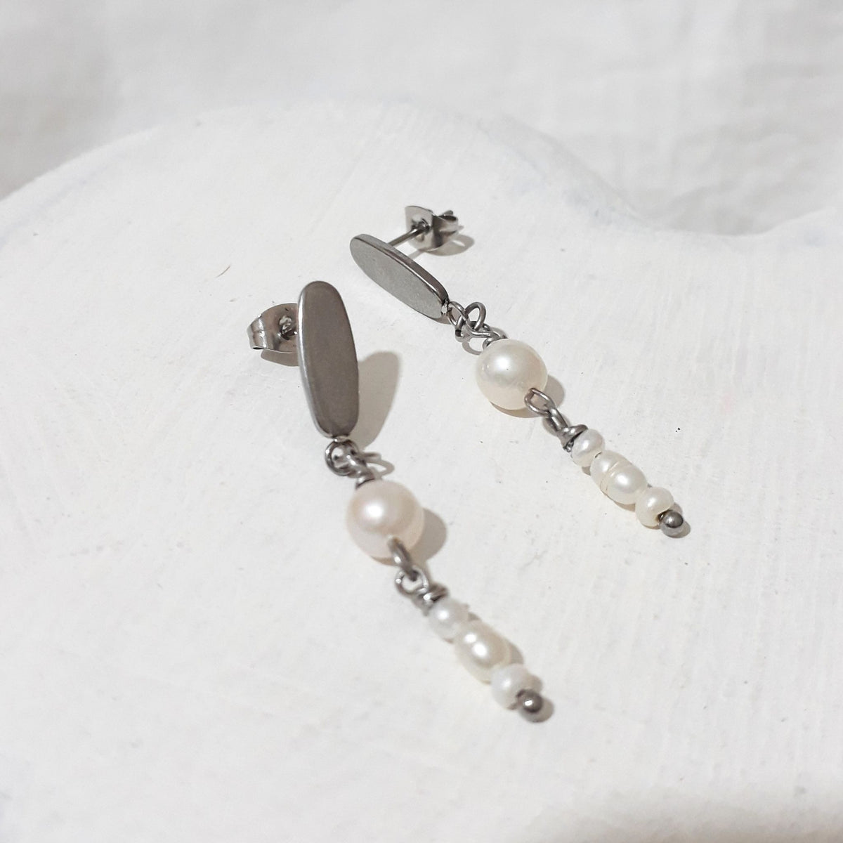 White round freshwater pearls linked above three small rice pearls beneath silver-tone oval studs with butterfly backs.