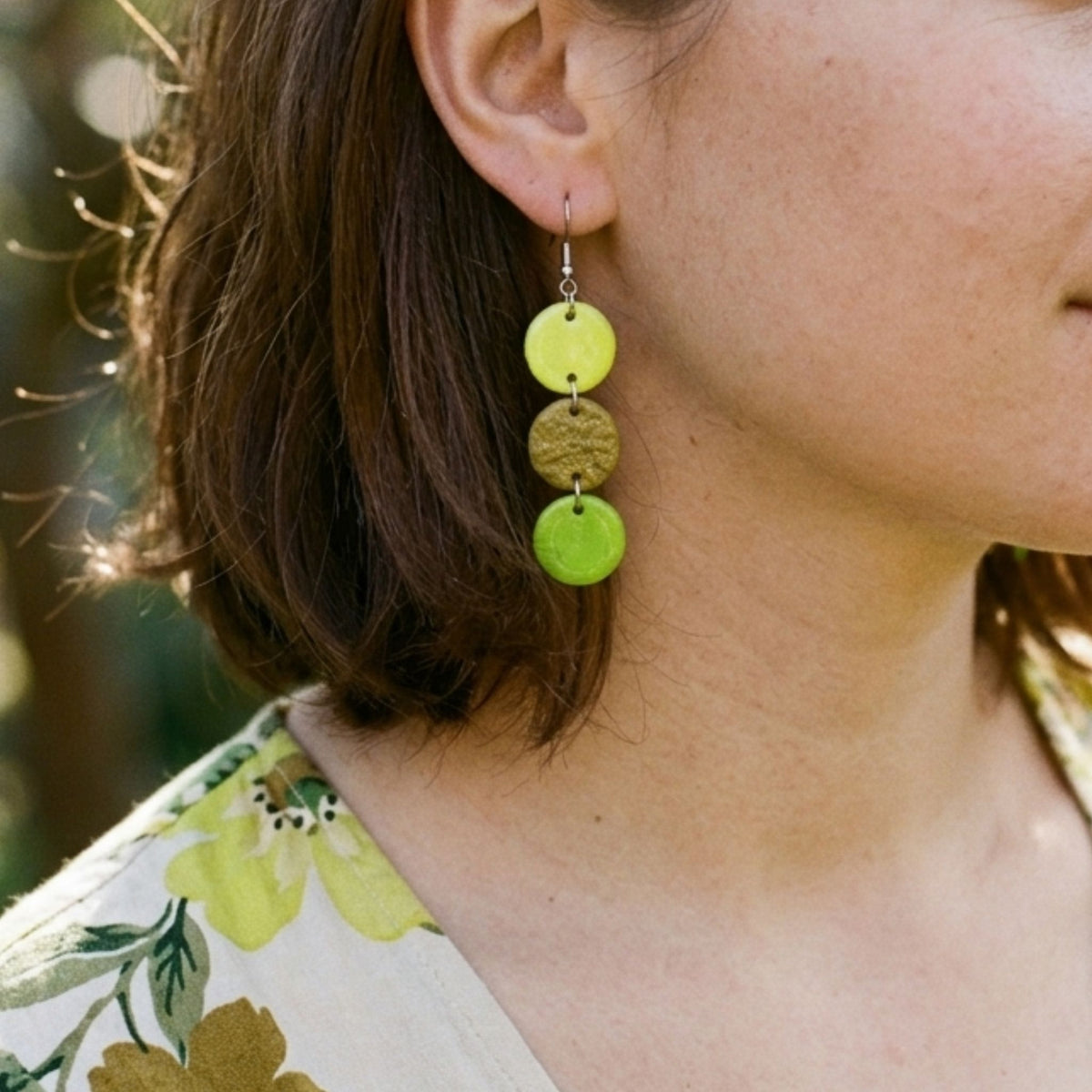 Woman wearing a polymer clay cascade earring in lemon yellow and green.
