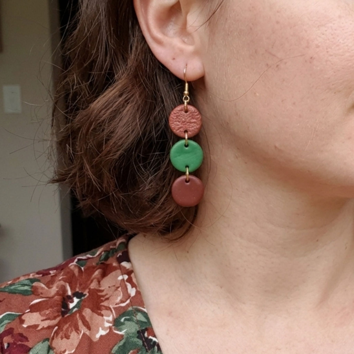Woman wearing brown and green polymer clay cascade earrings with gold plated ear hooks.