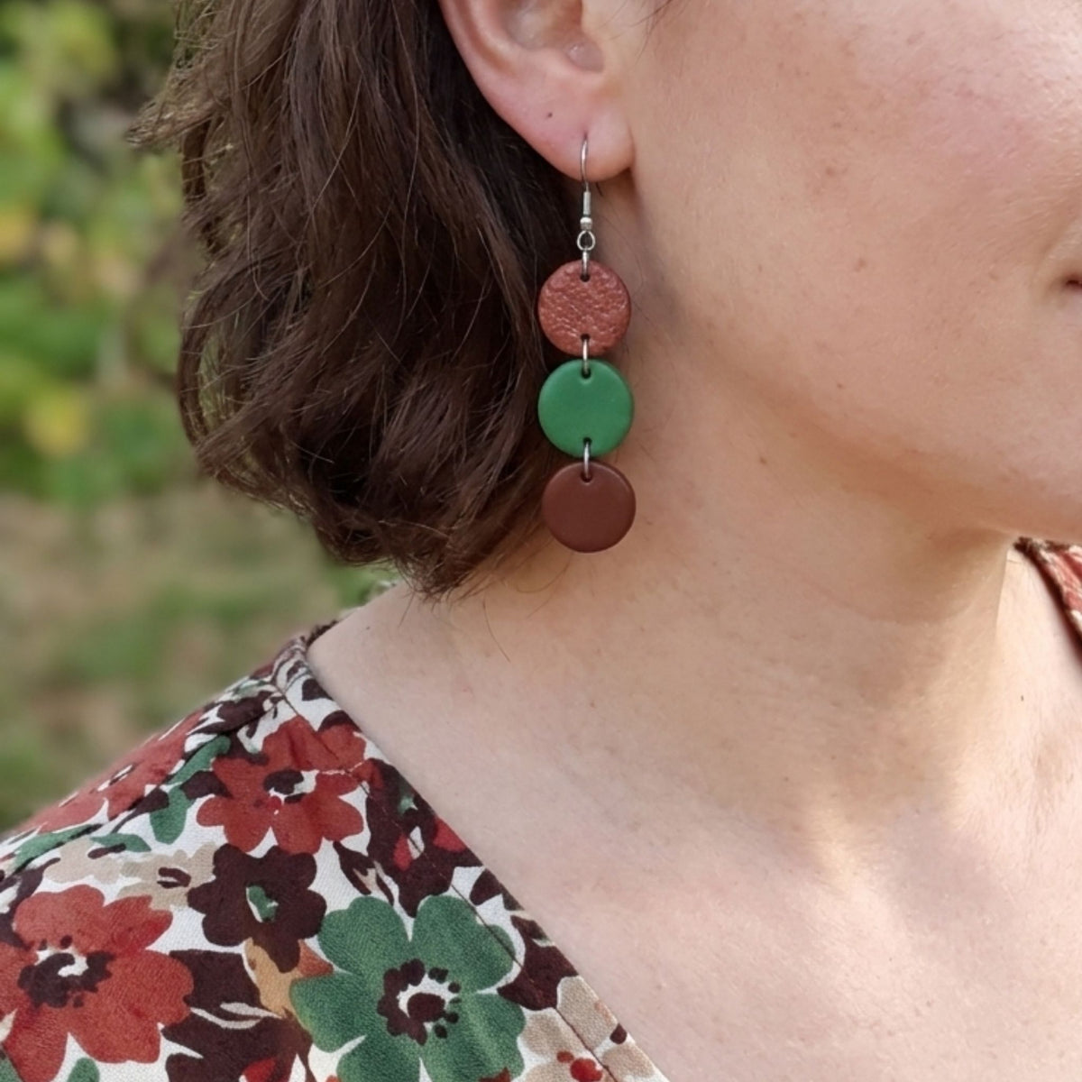 Woman wearing brown and green polymer clay cascade earrings.