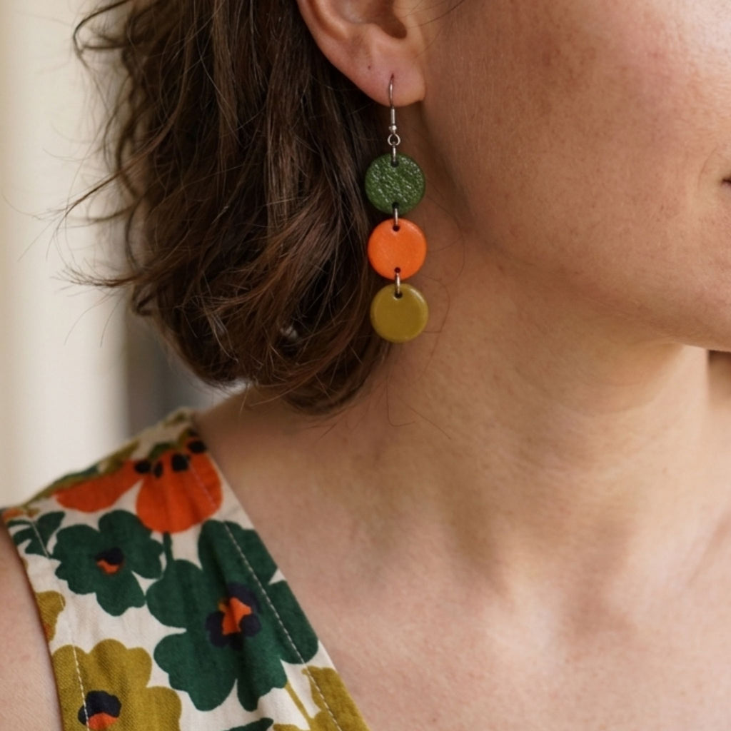 Woman wearing moss green, orange and olive polymer clay cascade earrings with stainless steel hooks.