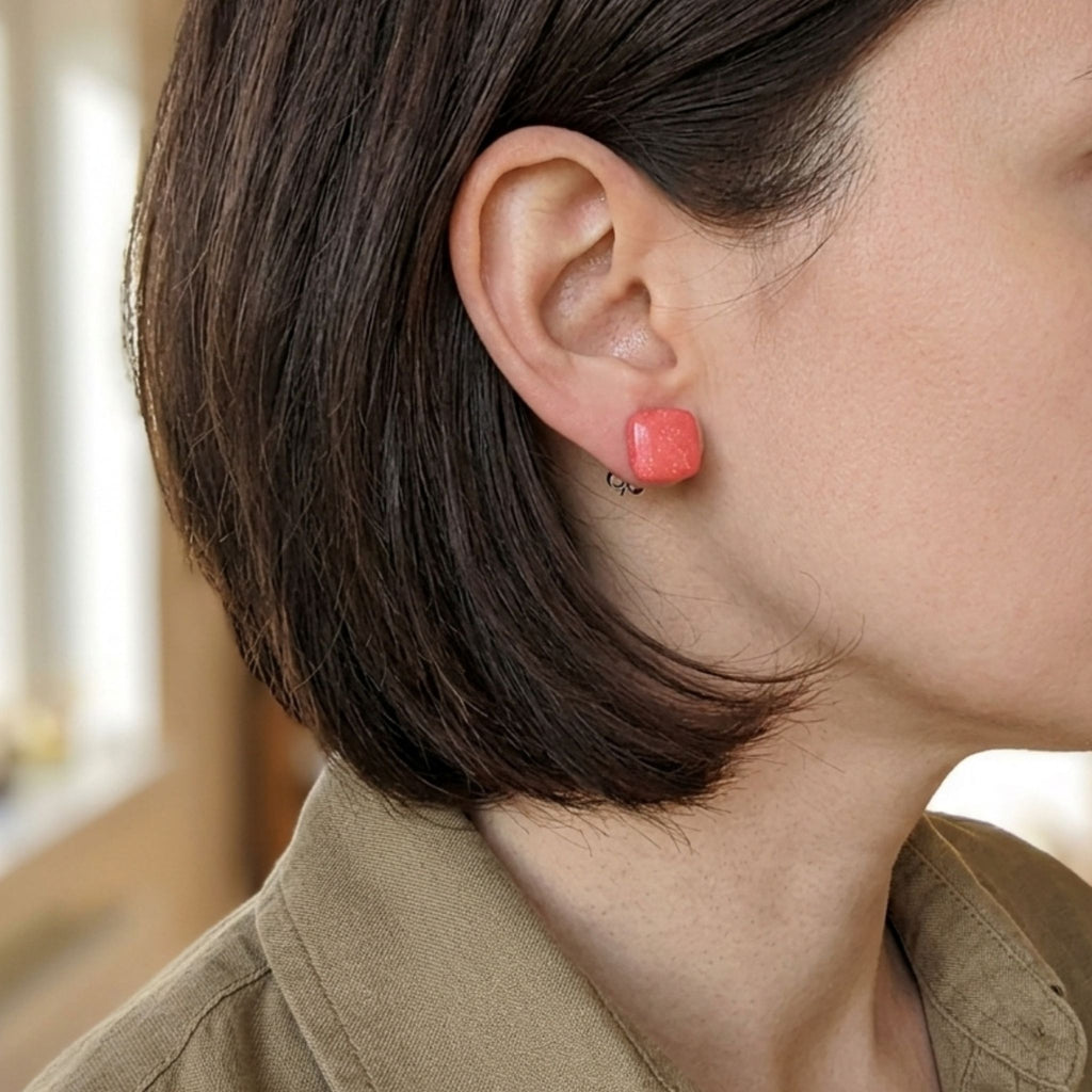 Woman wearing 14mm salmon pink square polymer clay stud earrings - lifestyle shot