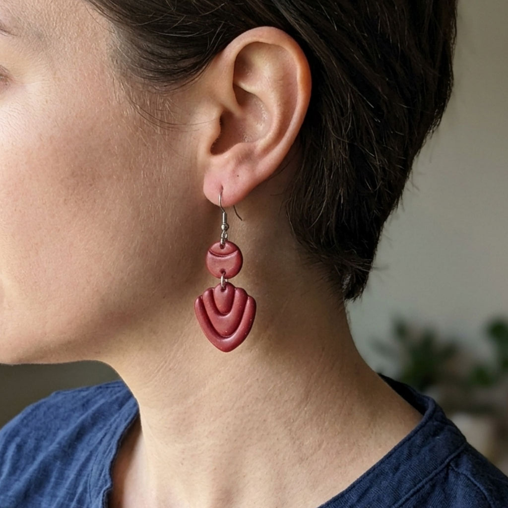 Woman wearing dark maroon-purple clay earrings