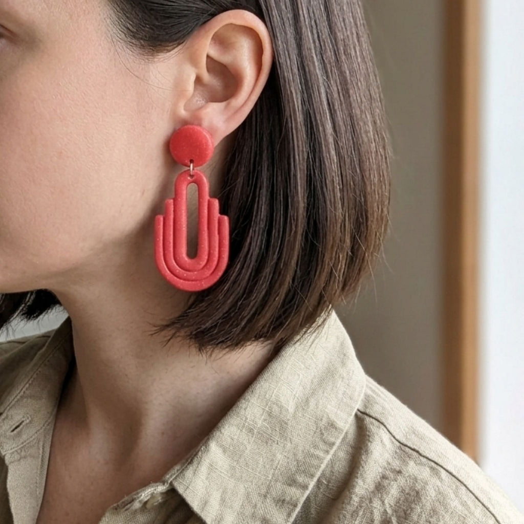 Woman wearing salmon pink Art Deco arch cutout polymer clay drop earrings - lifestyle shot
