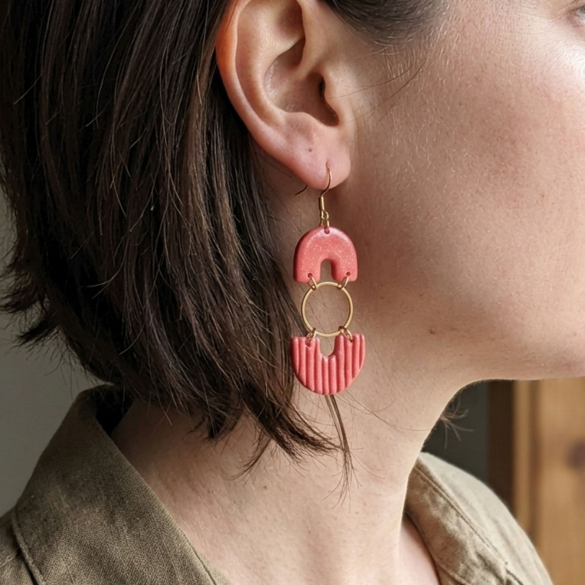 Woman wearing salmon pink arch and ribbed fan polymer clay dangle earrings with gold hardware - lifestyle shot