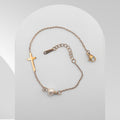Bracelet with cross charm and pearl on a light gray background
