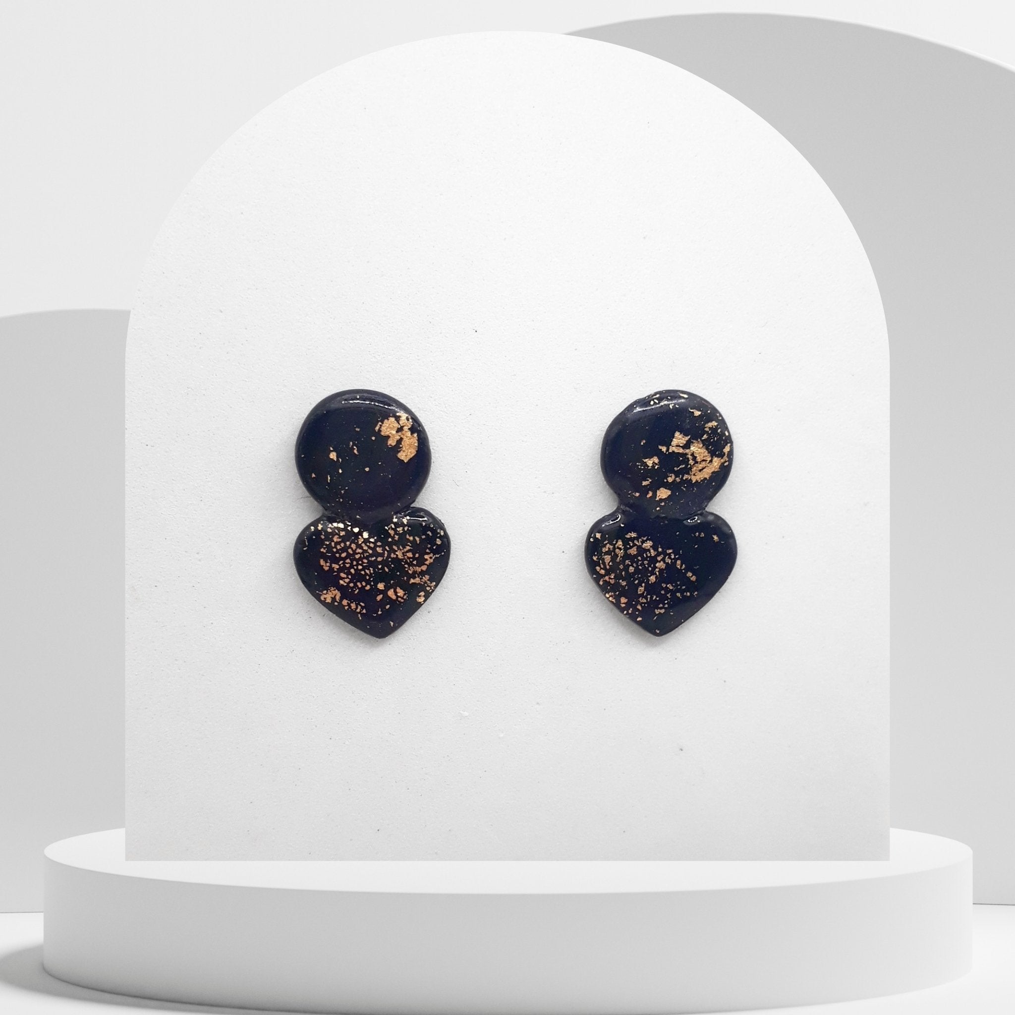 Heart-shaped earrings with gold speckles on a white stand