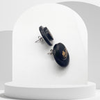 Black earrings with gold accents on a white stand
