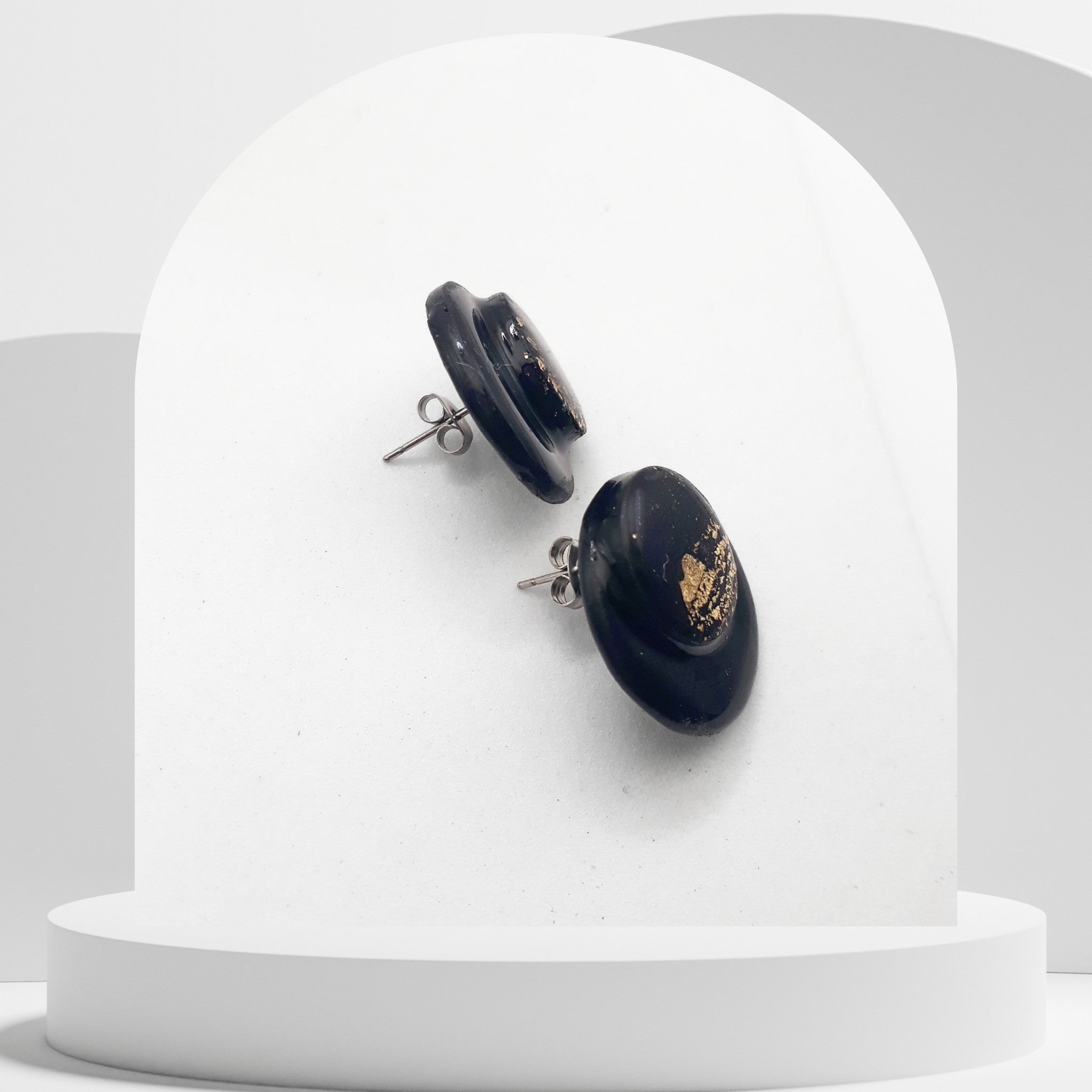 Black earrings with gold accents on a white stand
