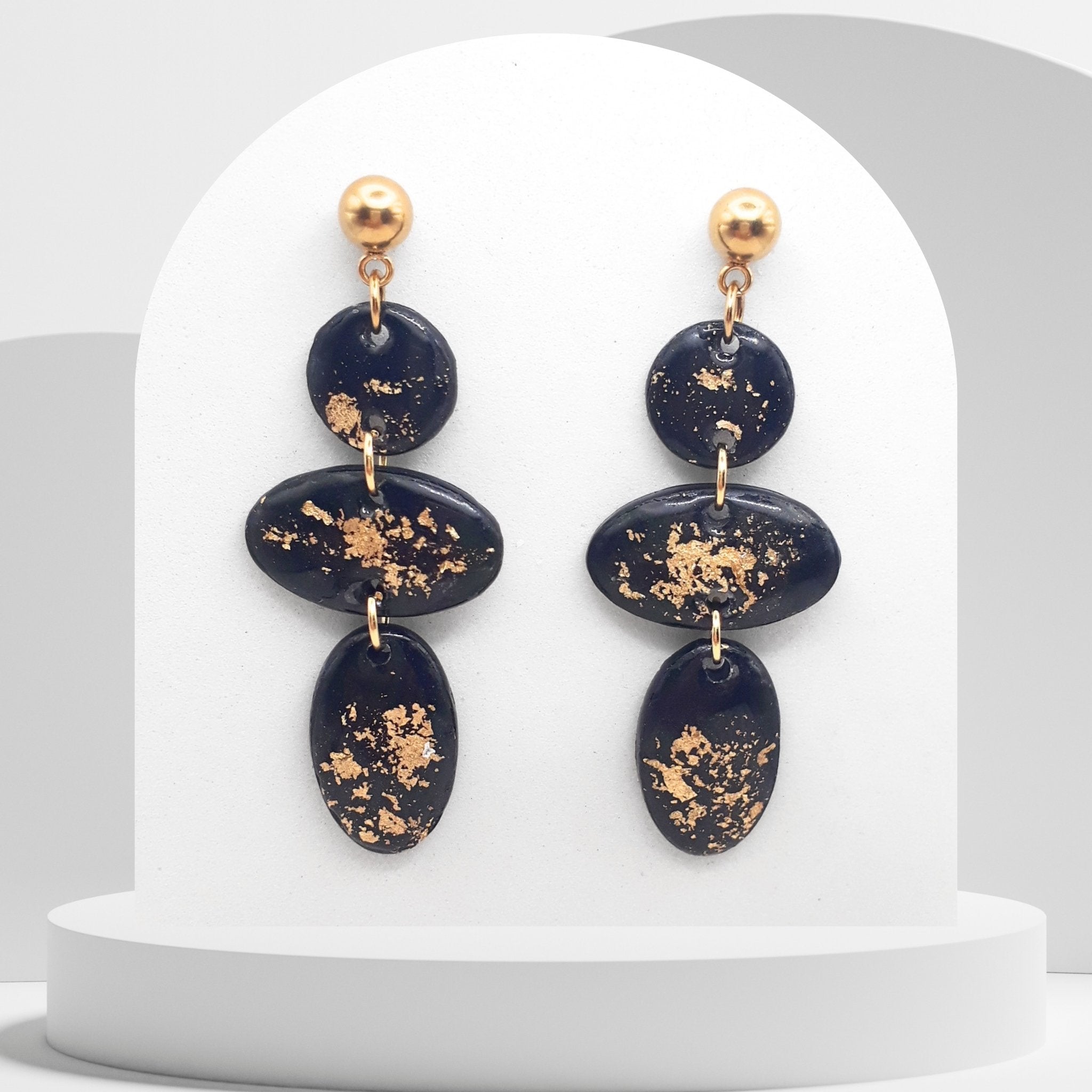 Handmade black and gold leaf polymer clay dangle earrings with geometric oval design