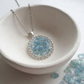 Handmade round aquamarine gemstone pendant necklace with rhinestone border on a stainless steel cable chain.