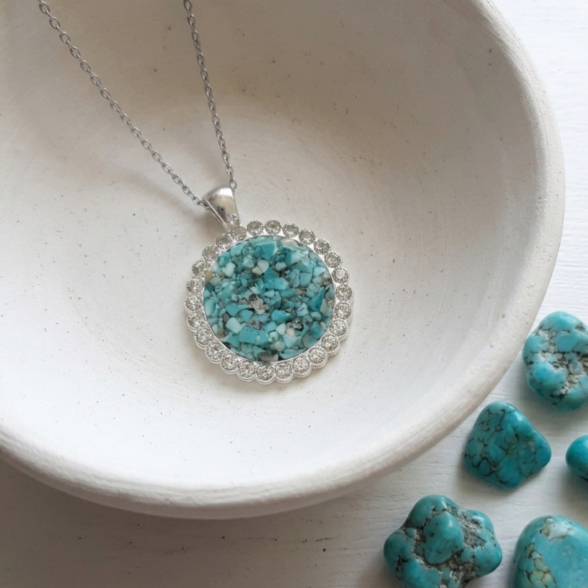 Handmade round turquoise gemstone pendant necklace with rhinestone border on a stainless steel chain.
