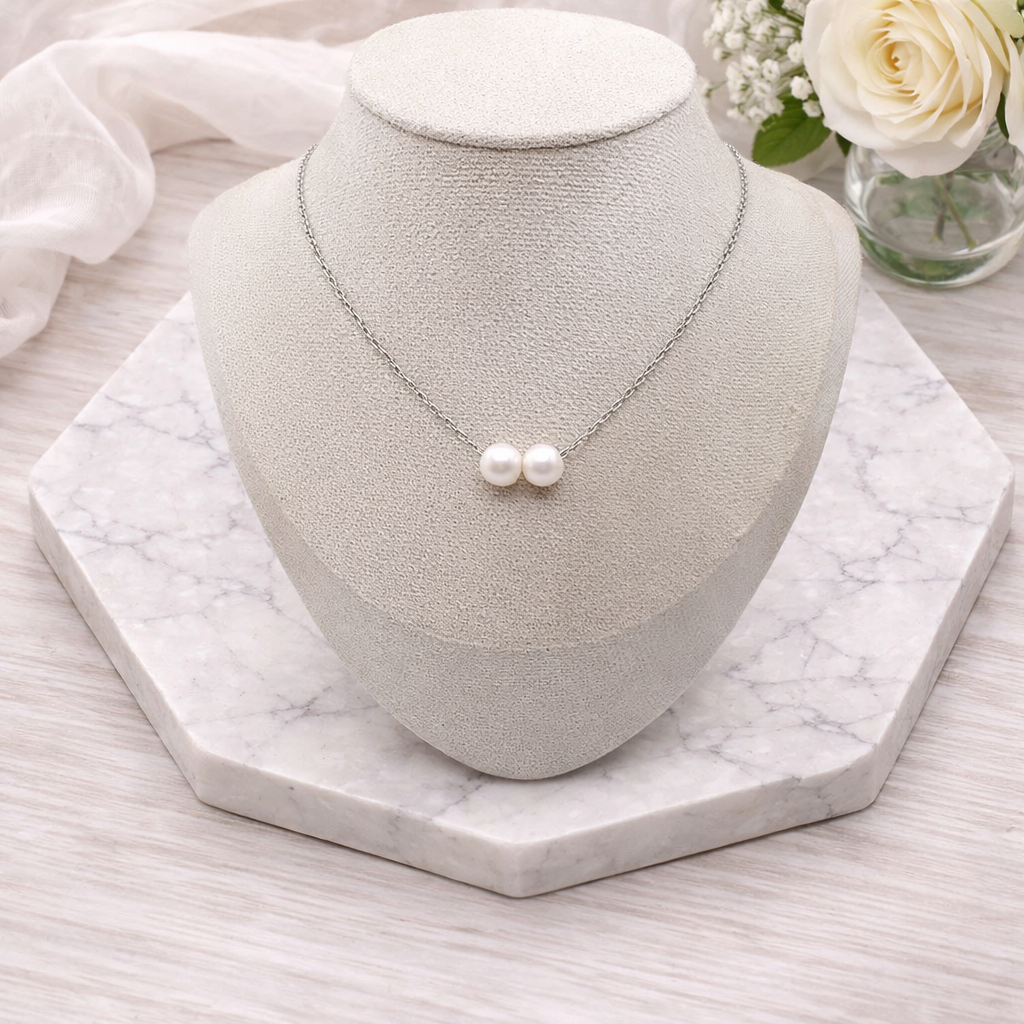 Double Floating Pearl necklace on a gray jewelry display with white roses in the background