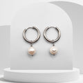 Silver hoop earrings with pearl drops on a white background