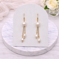 Cascade Pearl earrings on a white card with flowers in the background