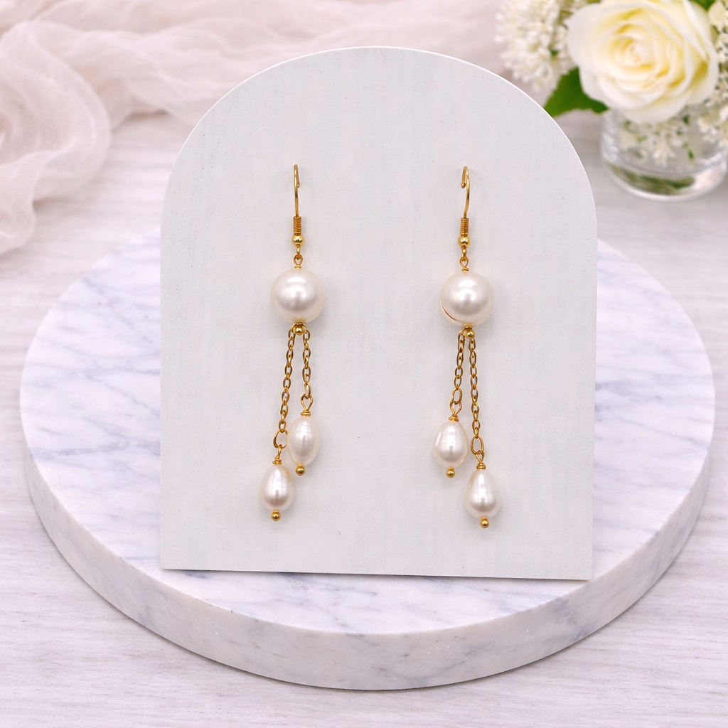 Cascade Pearl earrings on a white card with flowers in the background