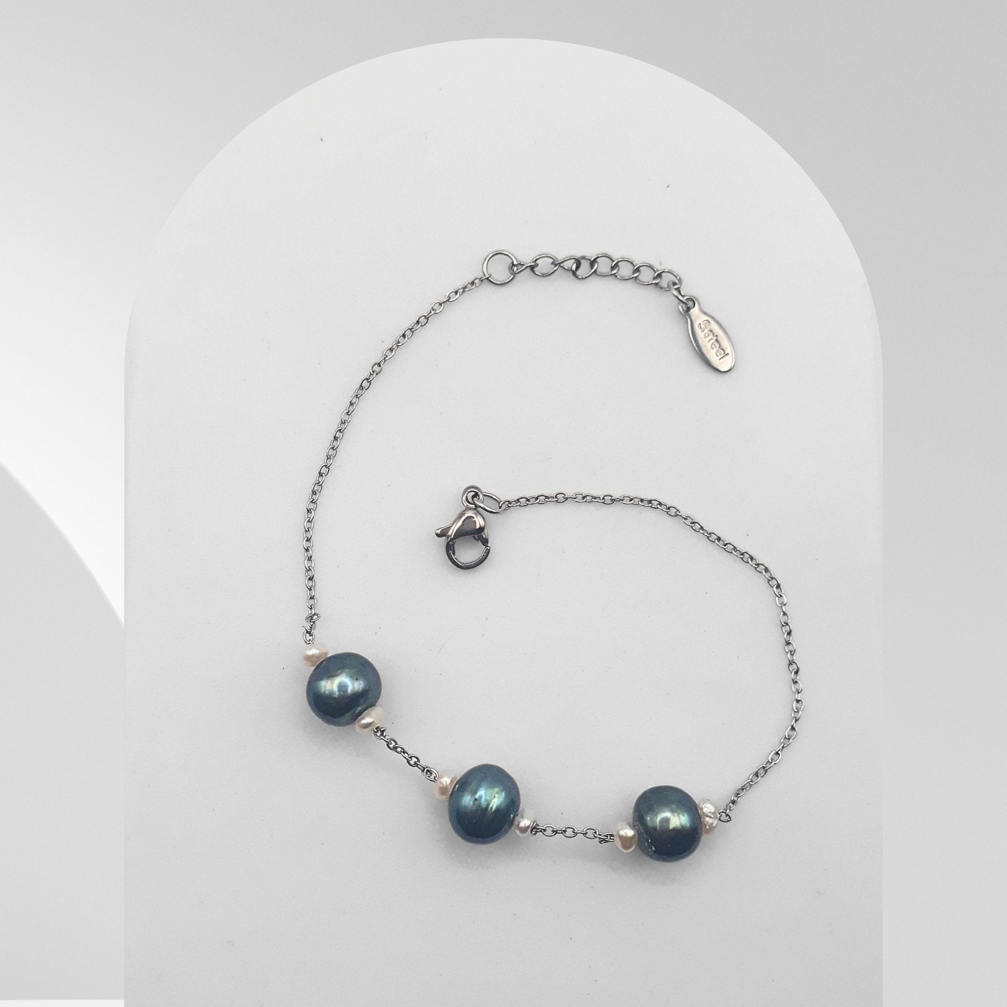 Handmade stainless steel bracelet featuring three dark green freshwater pearls accented with white rice pearls on a cable chain.