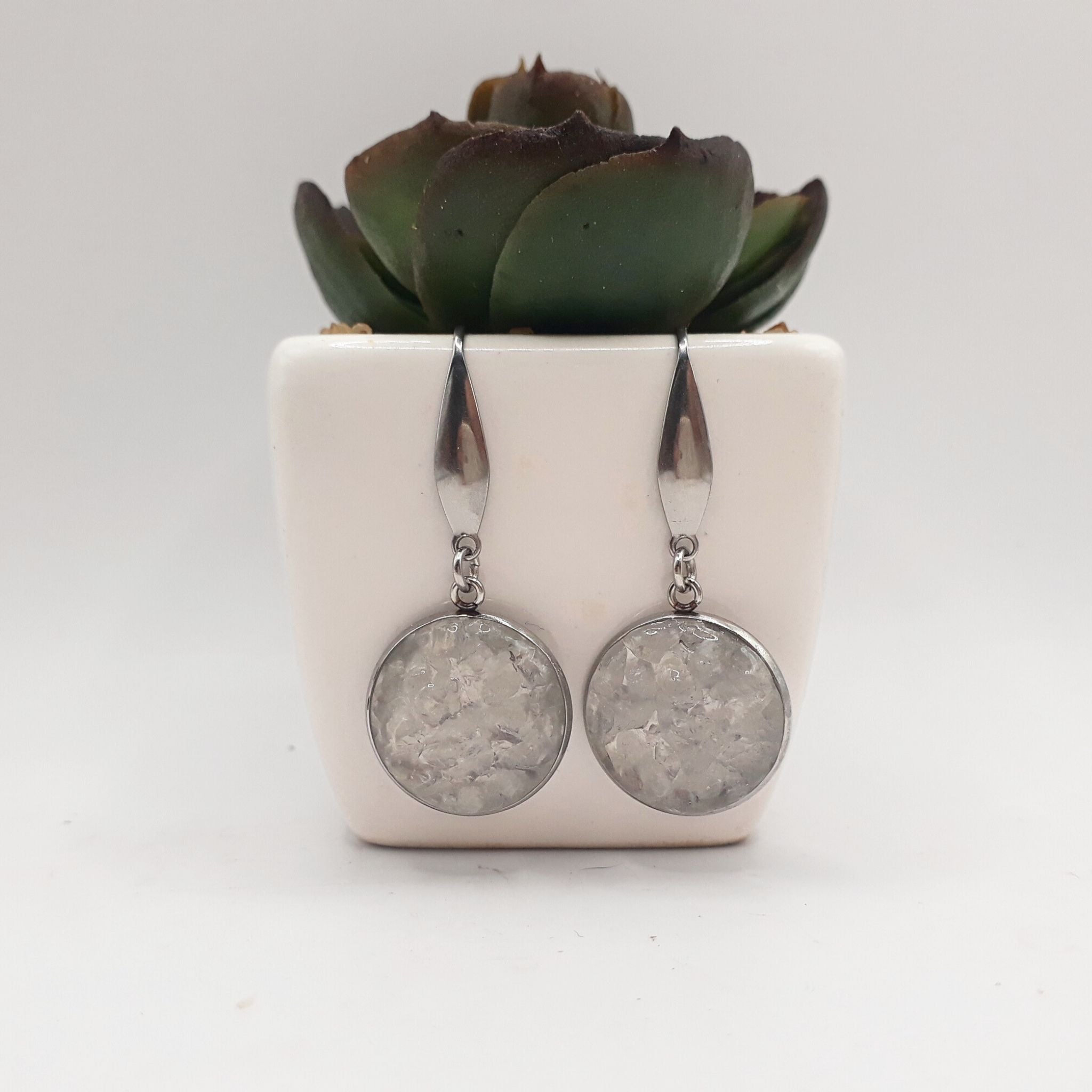 Handcrafted earrings with crushed clear quartz set in 16 mm stainless steel bezels, sealed in resin, hanging from elegant stainless steel ear hooks.