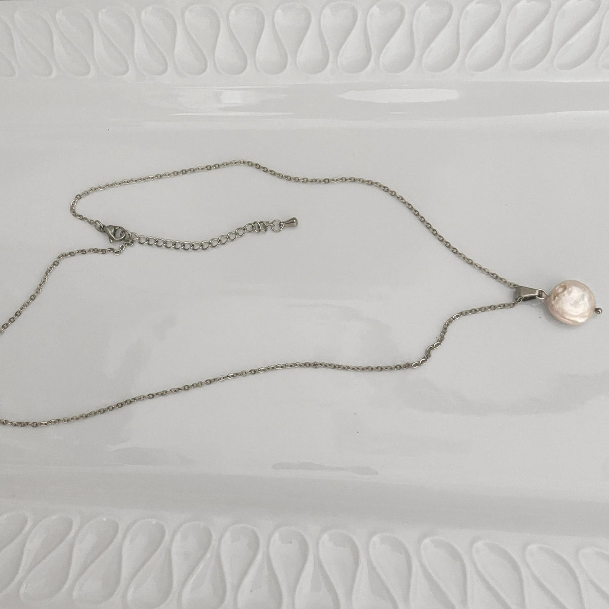 White Freshwater Coin Pearl Necklace – Stainless Steel lying flat on a white ceramic plate.