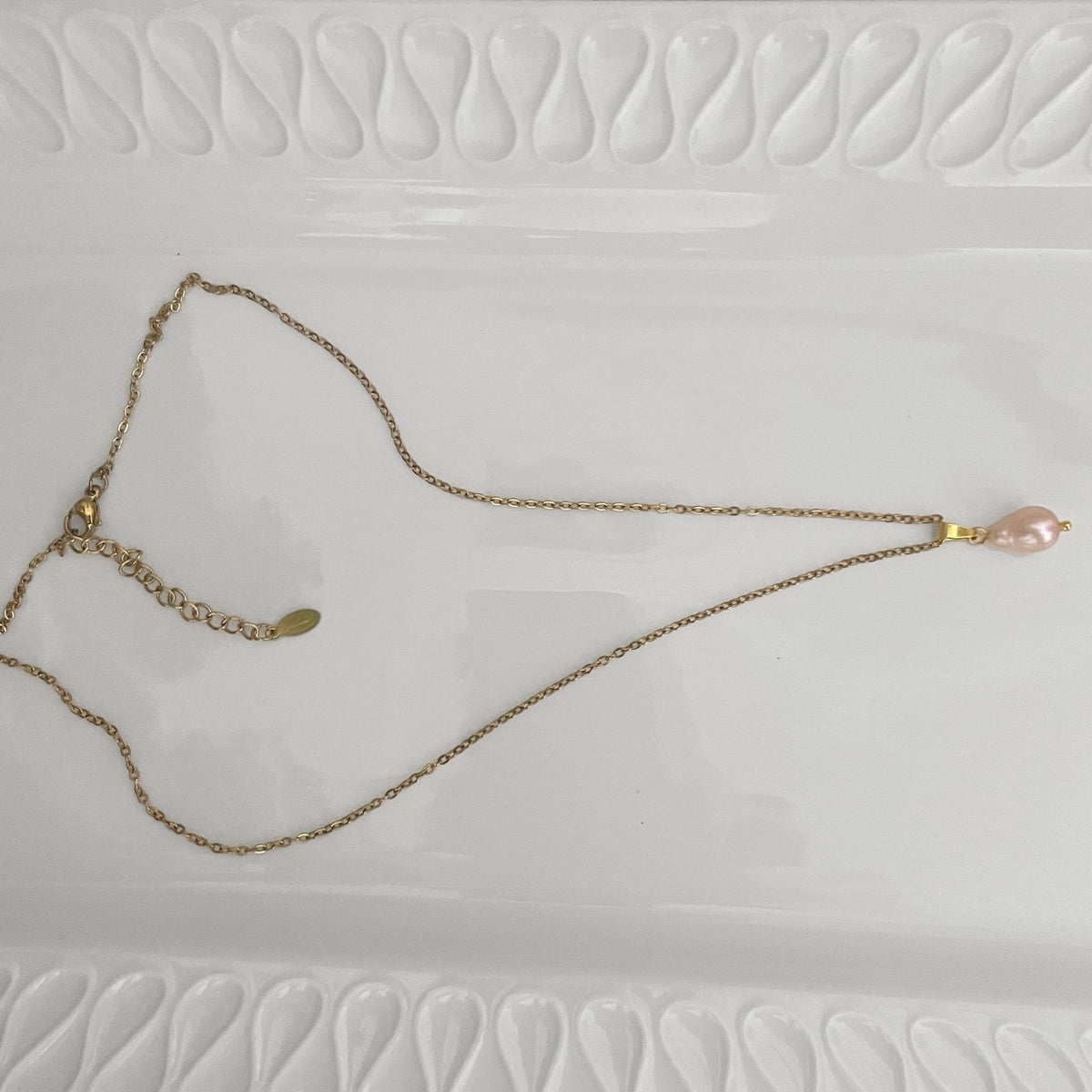 A delicate handmade necklace featuring a natural soft pink 7mm pear-shaped freshwater pearl on a gold-plated stainless steel chain.