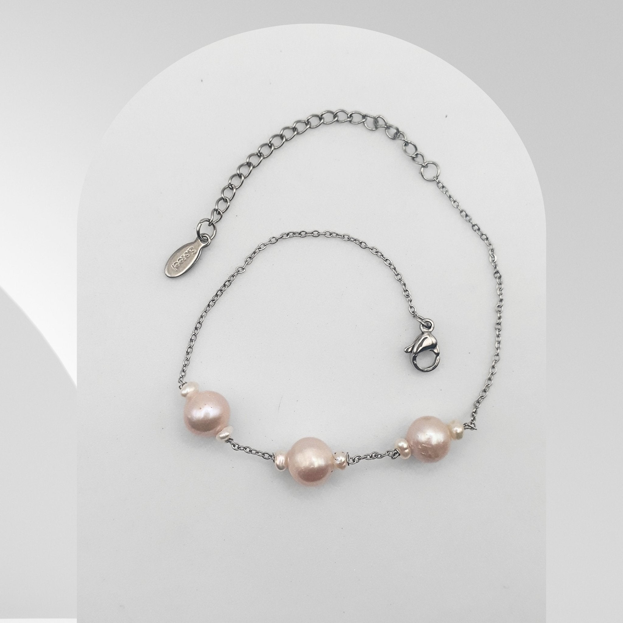 Handmade stainless steel bracelet featuring three soft pink freshwater pearls accented with white rice pearls on a cable chain.