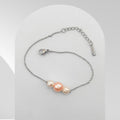 Handmade stainless steel bracelet featuring a peach-pink freshwater pearl with two peach-white freshwater pearls on a cable chain.