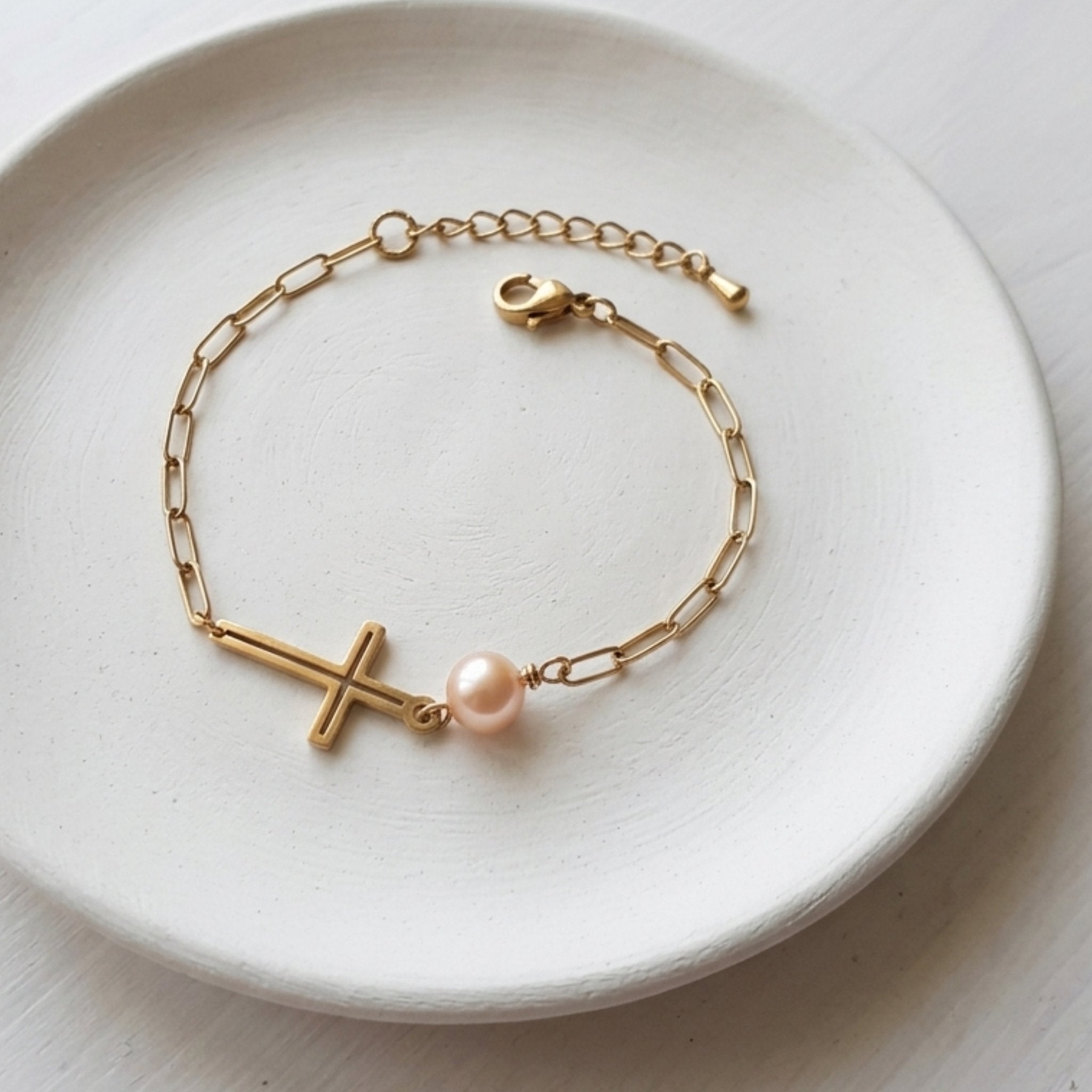 Handmade soft pink freshwater pearl bracelet with gold-plated cross and stainless steel paperclip chain.