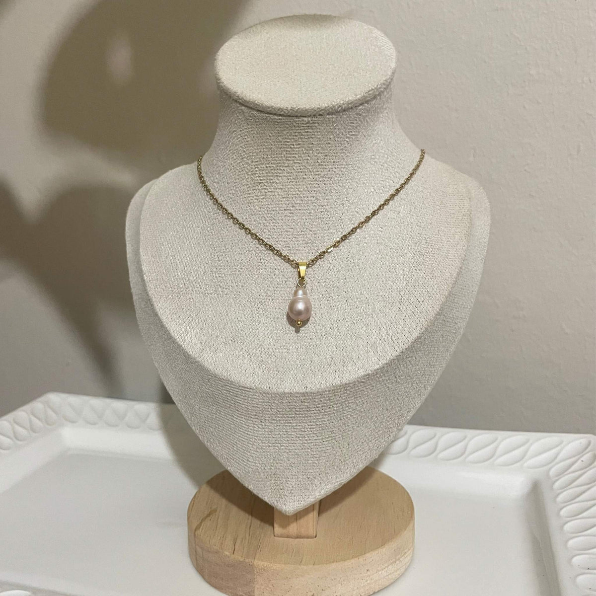 A delicate handmade necklace featuring a natural soft pink 7mm pear-shaped freshwater pearl on a gold-plated stainless steel chain.