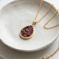 Handmade gold-plated teardrop necklace with crushed red garnet sealed in glass-like resin and gold stainless steel chain.