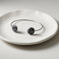 Handmade 304 stainless steel cuff bangle with 12mm bezels featuring natural crushed Snowflake Obsidian sealed with crystal-clear resin.