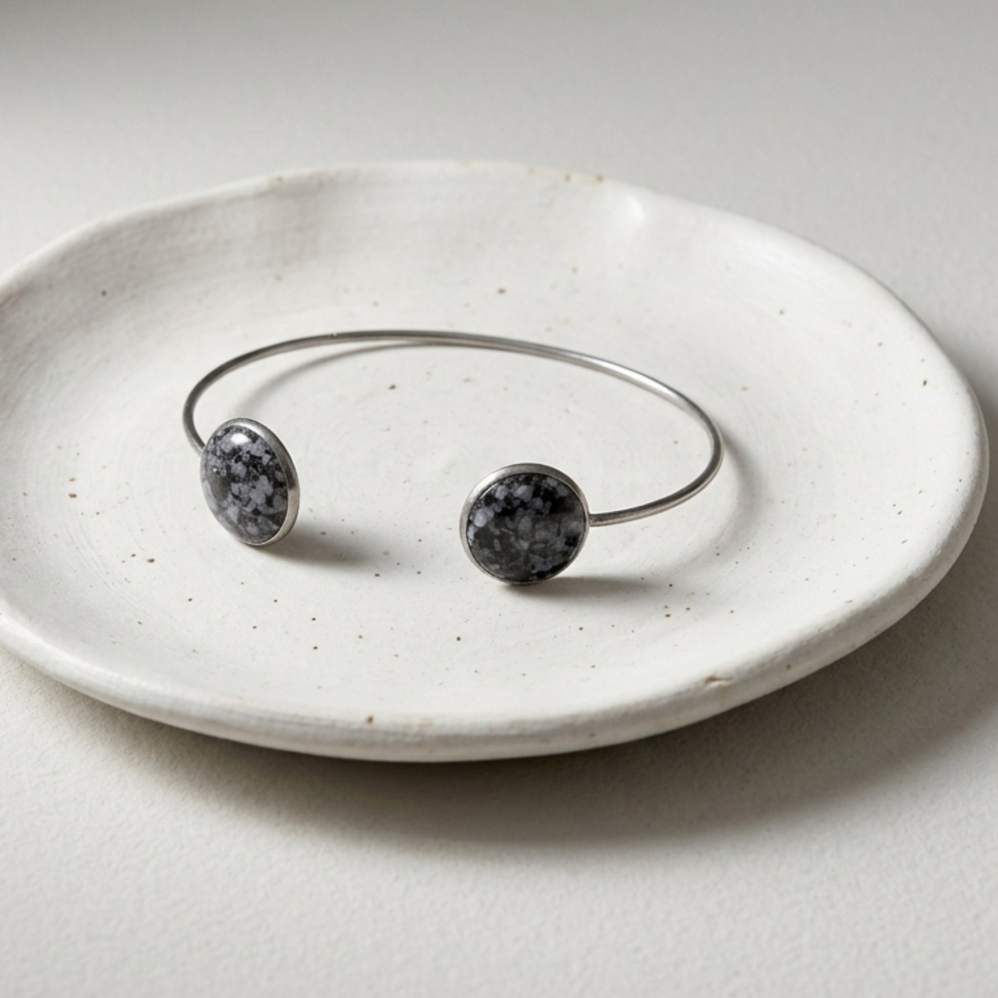 Handmade 304 stainless steel cuff bangle with 12mm bezels featuring natural crushed Snowflake Obsidian sealed with crystal-clear resin.