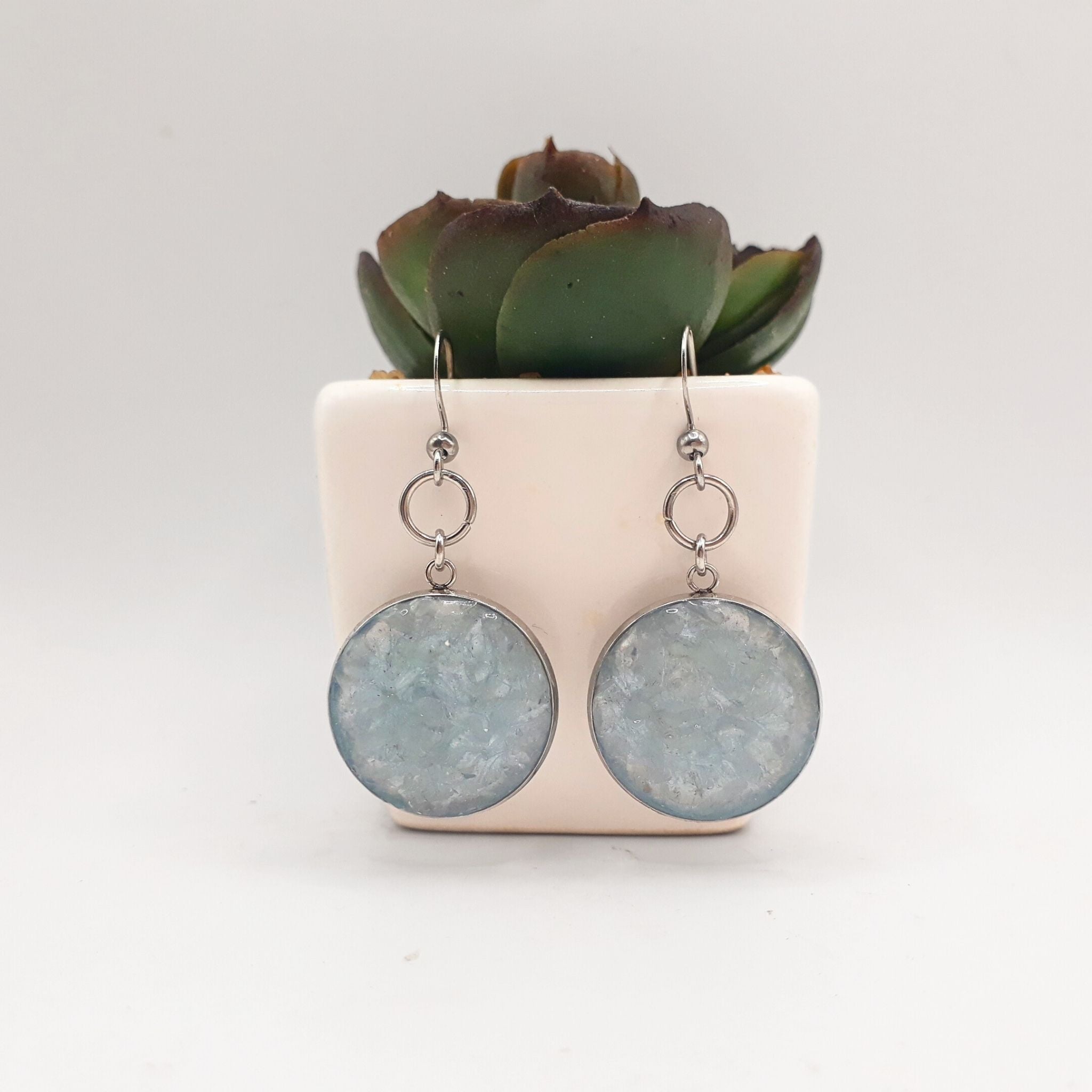 Handcrafted earrings with natural crushed clear quartz on a soft blue background, set in 20 mm stainless steel bezels and finished with elegant stainless steel hooks.
