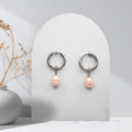 Handmade 316L stainless steel 16 mm huggie hoop earrings with removable 7 mm soft pink pear-shaped natural freshwater pearl charms.