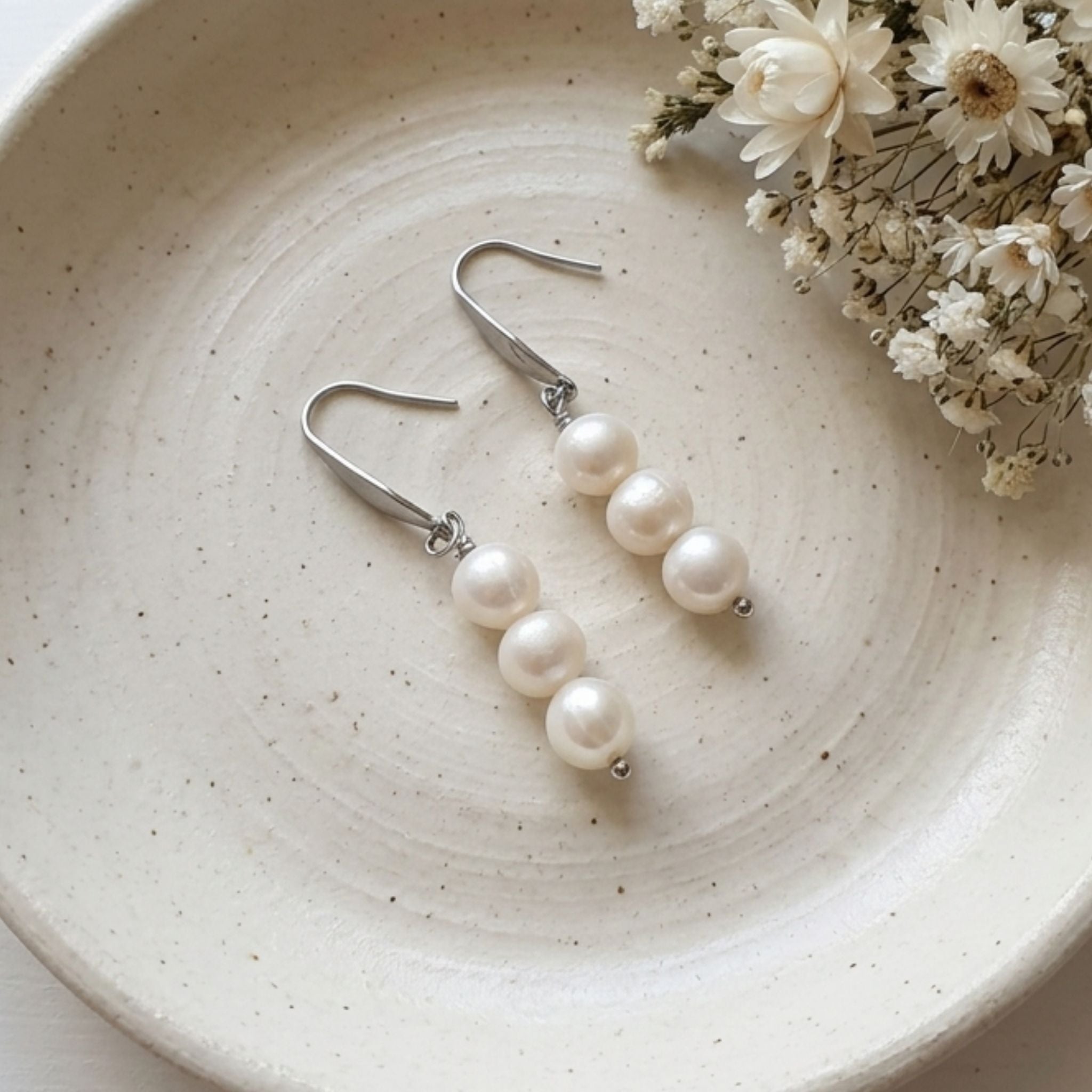 Three 7mm natural white freshwater pearls on 304 stainless steel drop earrings.