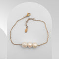 Three Pearl bracelet with gold chain on a white background