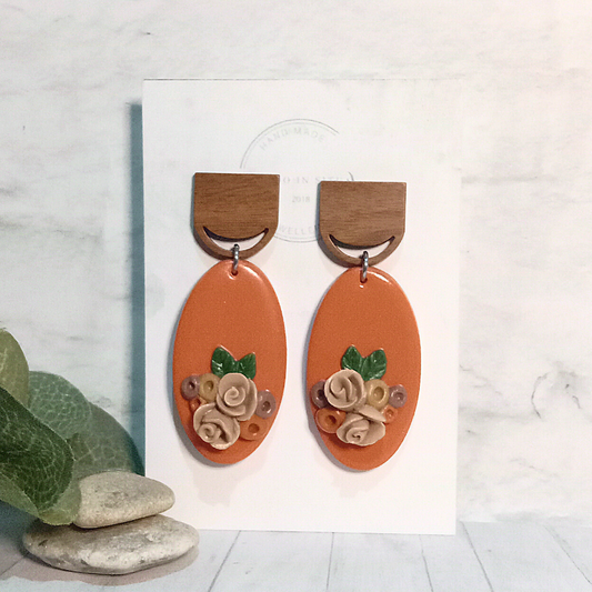 Elevate your style with our exquisite handmade polymer clay earrings. These stunning earrings feature an orange oval shape adorned with delicate handmade roses, adding a touch of elegance to any outfit. 