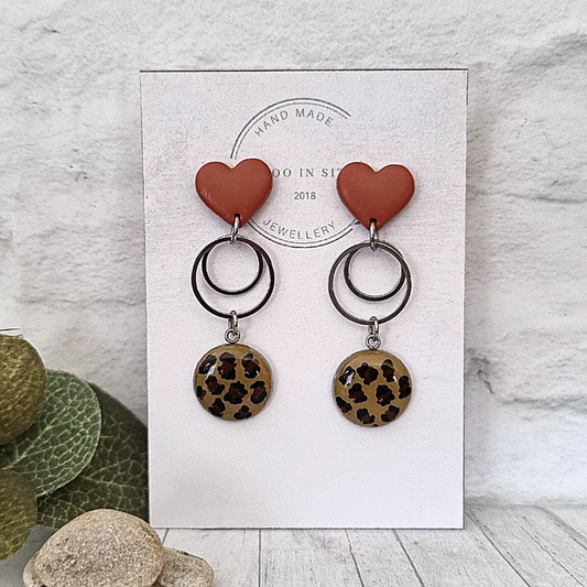 Don your ears in a wild style with these tan, brown polymer clay heart studs and hand-painted animal print stainless steel rounds.