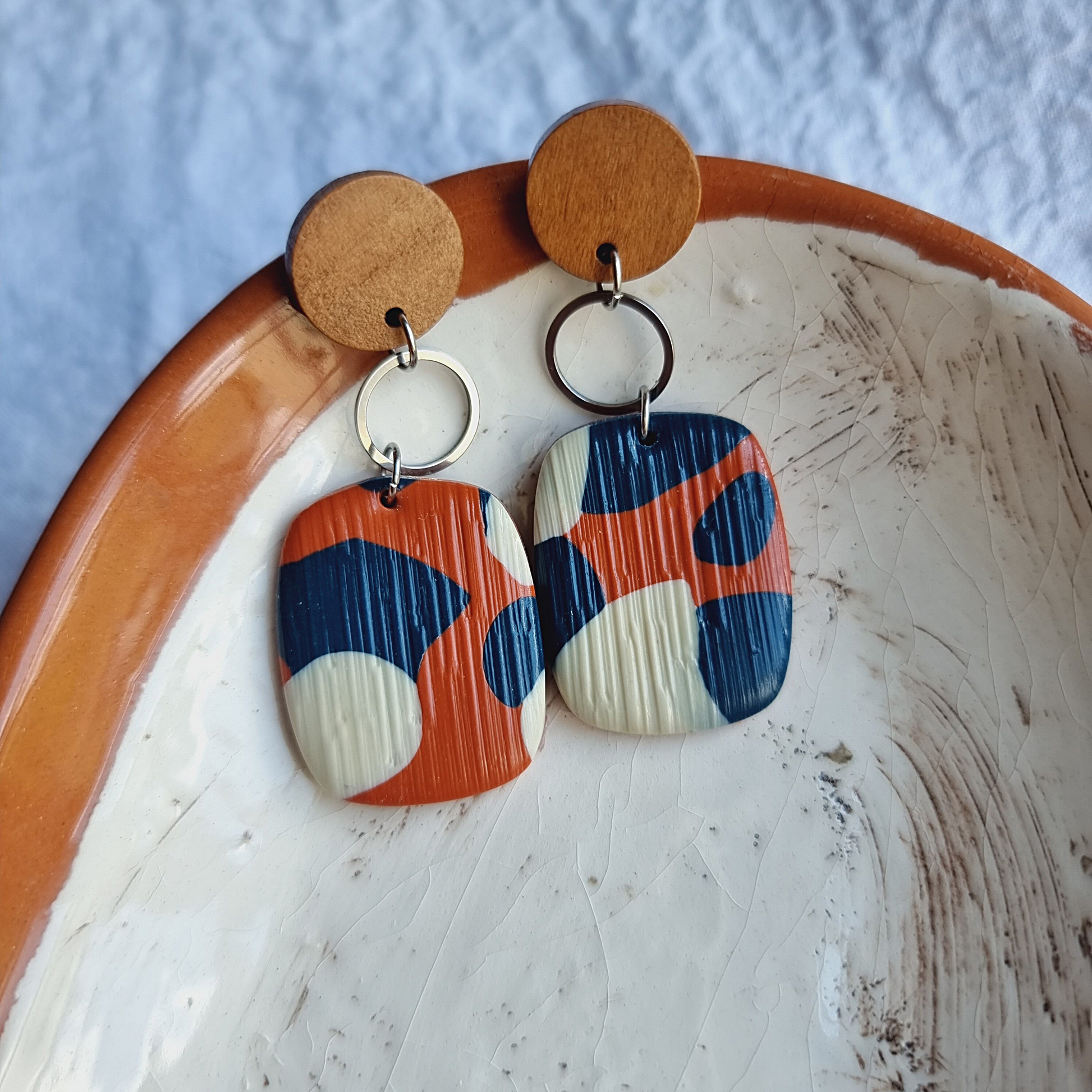 Embrace individuality with our unique handmade rectangle polymer clay dangle earrings. Featuring captivating blue, white, and brick colors, these earrings showcase a striking blend of tones.