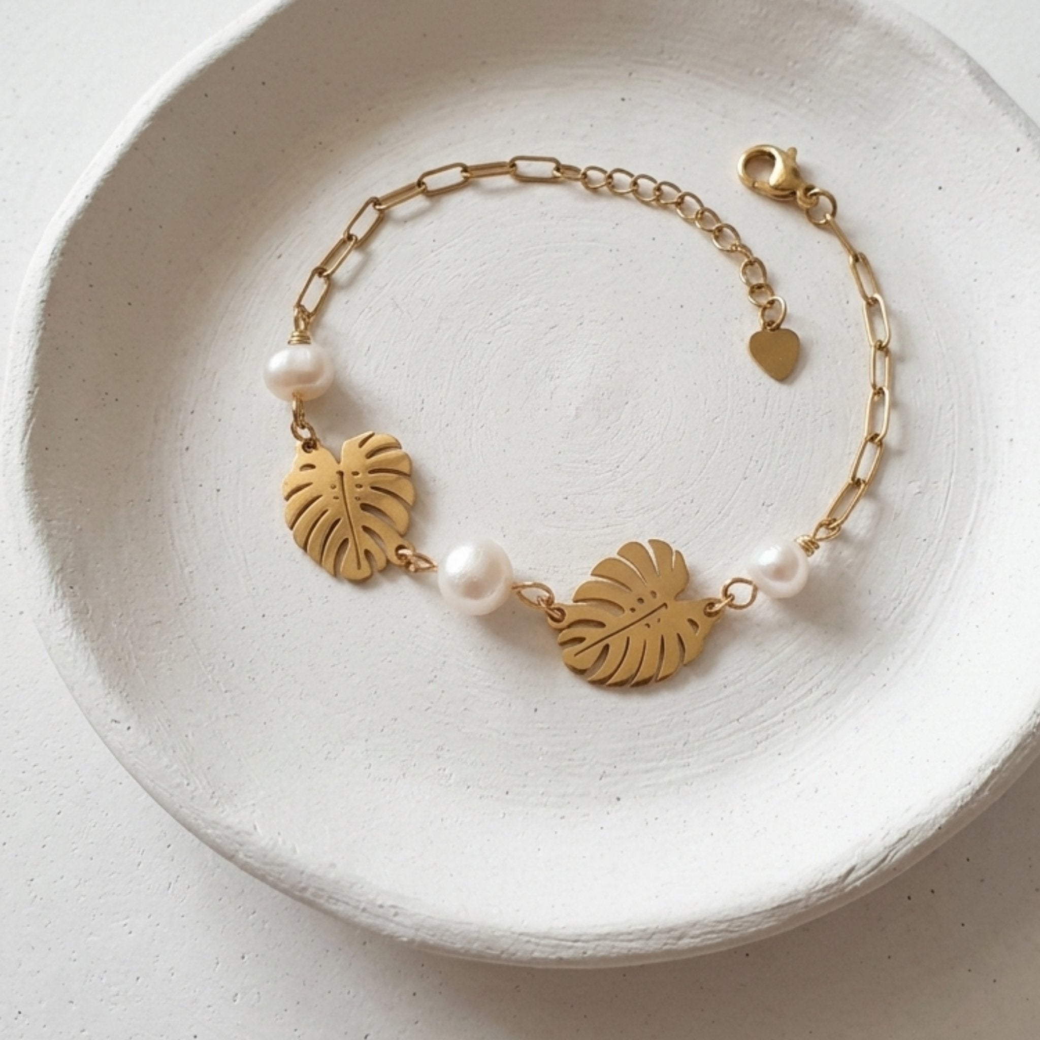 Handmade white freshwater pearl bracelet with gold monstera leaves and stainless steel paperclip chain.